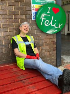 Photo of Jan wearing a yellow high viz vest, sitting on a red palette